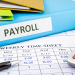 PAYROLL word on blue binder place on weekly time sheet and payroll summary report, human resources concept